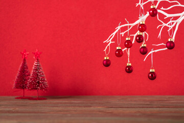 Wall Mural - Merry christmas with xmas tree and bauble ball at vivid red wall at wooden table.copy space for adding design