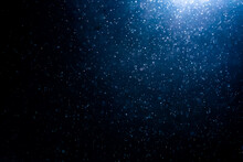 Blue Particles On Black Background With Cinematic Atmosphere. Glittering Sparkling Bokeh Overlay With Copy Space For Text.