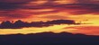 Atardecer en la Sierra de Guadarrama en Madrid, España. Cielo anaranjado con los últimos rayos de sol destacando la silueta de las montañas situadas al norte de Madrid.