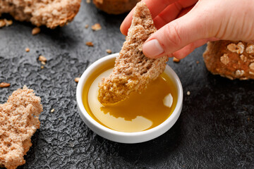 Wall Mural - Woman dipping bread into bowl of tasty olive oil