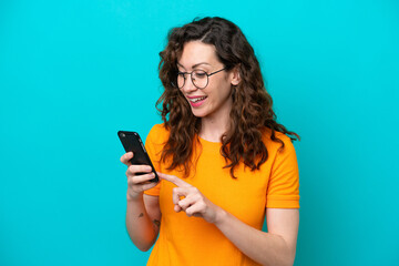 Wall Mural - Young caucasian woman isolated on blue background sending a message or email with the mobile