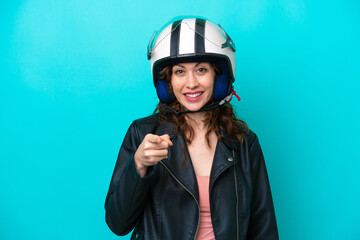 Wall Mural - Young caucasian woman with a motorcycle helmet isolated on blue background surprised and pointing front