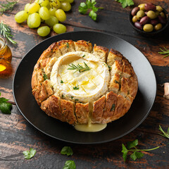 Wall Mural - Baked Camembert cheese in sourdough bread with rosemary, garlic, thyme