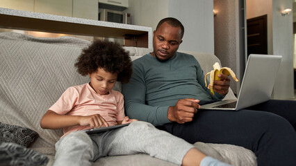 Wall Mural - Father looking at little son using digital tablet