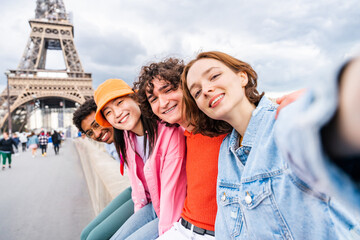 multiethnic group of young happy teens friends bonding and having fun while visiting eiffel tower ar