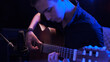 © Valua Vitaly - Man plays guitar. Young man plays a musical instrument. Musician records his composition in a music Studio using professional microphone
