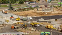 Aerial View Of Large Road Construction Site With Several Industrial Machines Timelapse. Earthmoving Equipment With Excavators And Cranes Moving Concrete Plates.