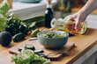 © gstockstudio - Close-up of unrecognizable man pouring olive oil into the bowl with fresh salad