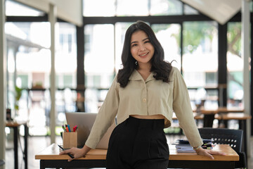 Confidently Asian businesswoman standing in front of the office workplace.