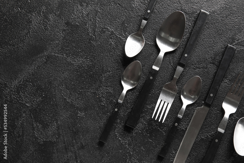 Different cutlery on dark background, top view