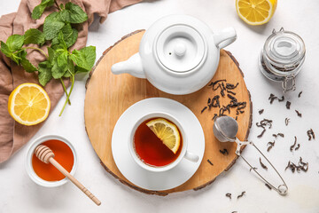 Board with cup of black tea, lemon, teapot and honey on white background