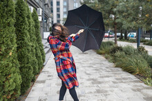 Woman Trying To Hold Her Umbrella In Strong Wind