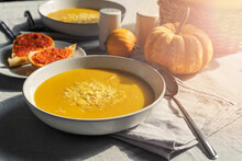 Bowl Of Homemade Creamy Pumpkin Soup With Cheese And Bread With Red Pepper