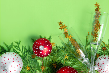 Wall Mural - Multicolored Christmas balls  with tree branches and glasses of champagne on green paper background. New Year creative greeting card.