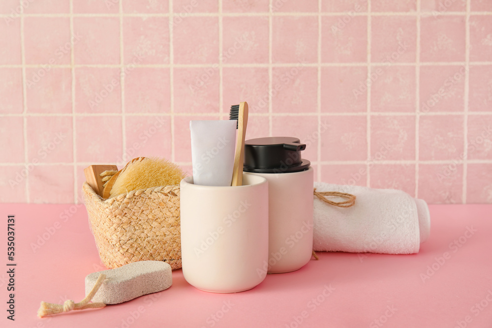 Bath accessories on table near pink tile wall