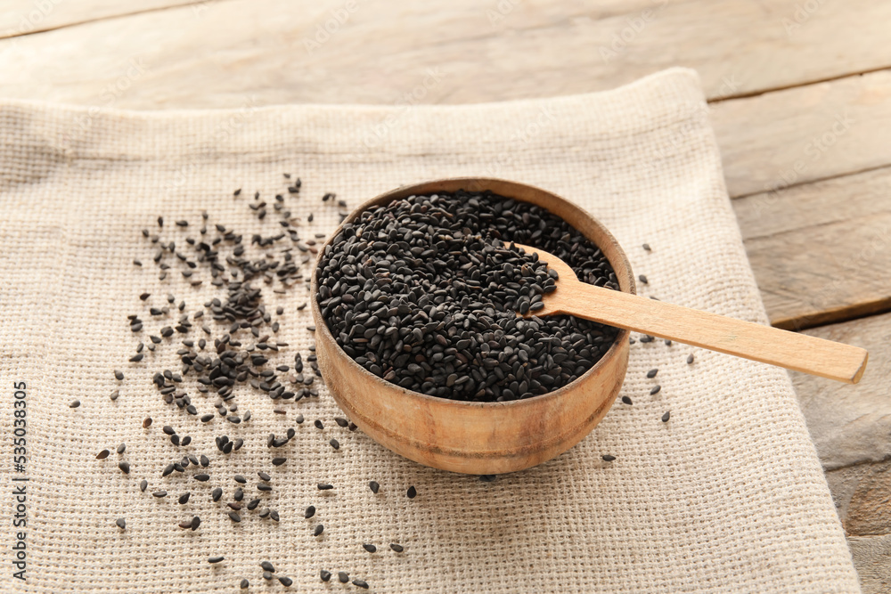 Bowl of black sesame seeds on wooden table