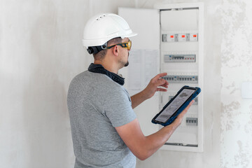 Wall Mural - Electrical technician looking focused while working in a switchboard with fuses.