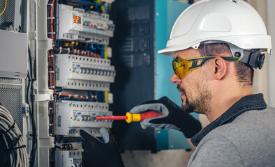 Wall Mural - Man, an electrical technician working in a switchboard with fuses.