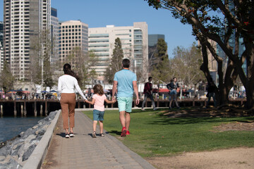 Wall Mural - Back view of happy family walking the city street, casual lifestyle.