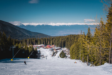 Wall Mural - Winter landscape with panorama of Bansko above the clouds. Famous ski resort in Bulgaria. View of the ski slopes and the Pirin Mountains