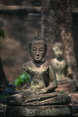 Wall Mural - Ancient old ruin of Buddha statue carved from sandstone was destroyed and abandoned left in the Wat U Mong Temple.