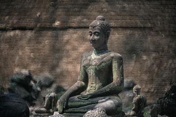 Wall Mural - Ancient old ruin of Buddha statue carved from sandstone was destroyed and abandoned left in the Wat U Mong Temple.