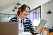 © bongkarn - Charming Asian female with eyeglasses and headphones using digital tablet