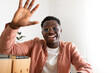 © Daniel - African american young man looking at camera waving hand saying hello during video call.