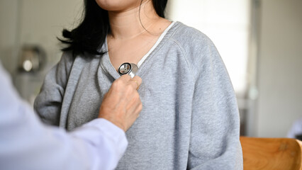 Wall Mural - A doctor cardiologist checking up her female patient, listening heartbeat by stethoscope.