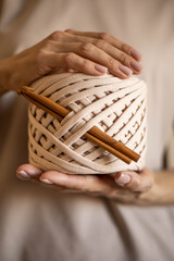 Wall Mural - Closeup beautiful female hands hold hank reel of beige ribbon yarn and wooden crochet needles