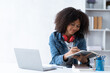 © PaeGAG - Focused young African female college student working on a laptop on living room.