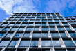 glass and aluminum office tower detail in diminishing perspective. abstract low angle view. modern architecture and design concept. blue sky and white clouds. reflection on the glass. vertical bands.