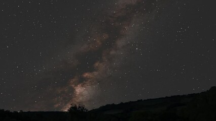 Wall Mural - Milky Way Galaxy Rising Over Countryside Hills at Night with Stars and Galactic Centre Black Hole 4K