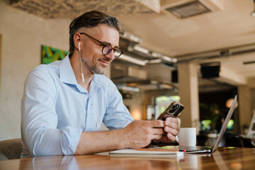 European grey man using mobile phone while working at office