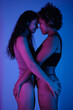 © Clique Images - Vertical medium side view shot of young lesbian Black and Caucasian women in underwear standing close holding hands on butts of each other