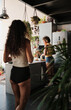 © Clique Images - Vertical selective focus shot of unrecognizable young woman entering kitchen in morning where her girlfriend cooking breakfast