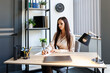 © nazariykarkhut - A beautiful young woman is working with papers at her workplace in the office. A woman signs documents while sitting at a desk