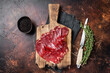 Turkish pastrami (kayseri pastirma), dried beef meat with spices. Dark background. Top view