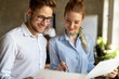 © NDABCREATIVITY - Portrait of two young business people talking about documents in office