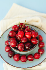 Top view of red sweet cherry on blue plate close up. Vegan, summer food concept. Diet