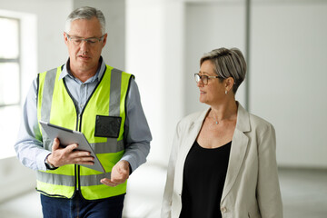 Professional senior engineer builder showing clients around in the new development building