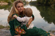 © rubchikova - A young mother and daughter are sitting near the river