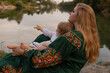 © rubchikova - A young mother and daughter are sitting near the river