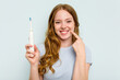 © Asier - Young caucasian woman holding electric toothbrush isolated on blue background