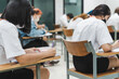 © EduLife Photos - College students writing on final examination papers in the classroom concentrately.