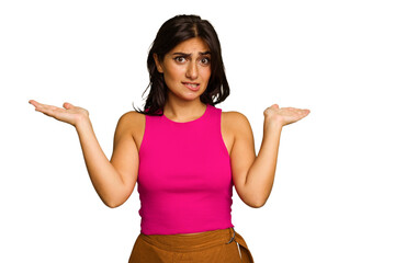 Young Indian woman isolated on green chroma background confused and doubtful shrugging shoulders to hold a copy space.