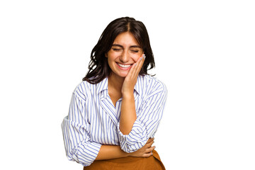 Young Indian woman isolated on green chroma background laughs happily and has fun keeping hands on stomach.