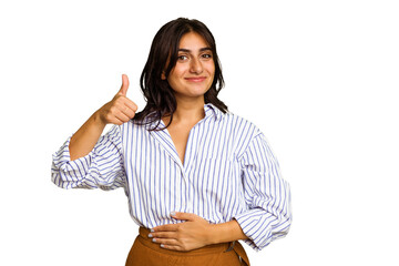 Young Indian woman isolated on green chroma background touches tummy, smiles gently, eating and satisfaction concept.