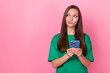 © deagreez - Photo of nice adorable sweet girl with long hairdo wear green t-shirt look empty space hold smartphone isolated on pink color background