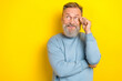Photo of thoughtful funky man pensioner dressed blue pullover arm eyewear looking empty space isolated yellow color background